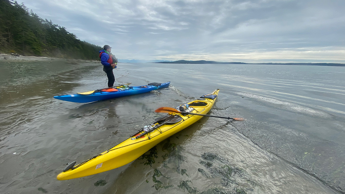 person stands next to kayaks