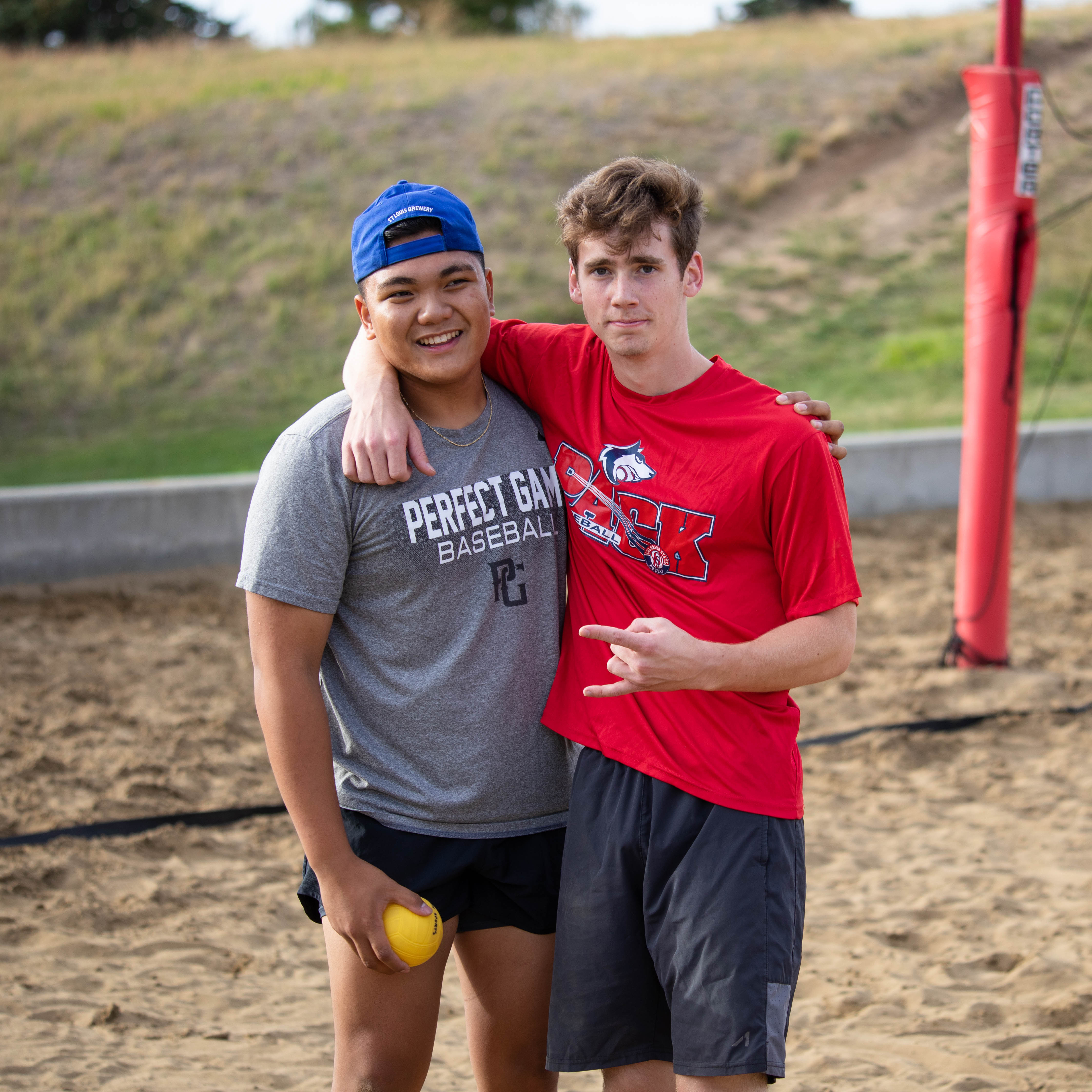 two students by sand volleyball court