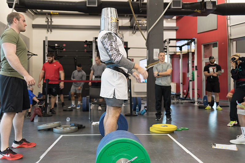 person wearing knights costume prepares to lift barbell